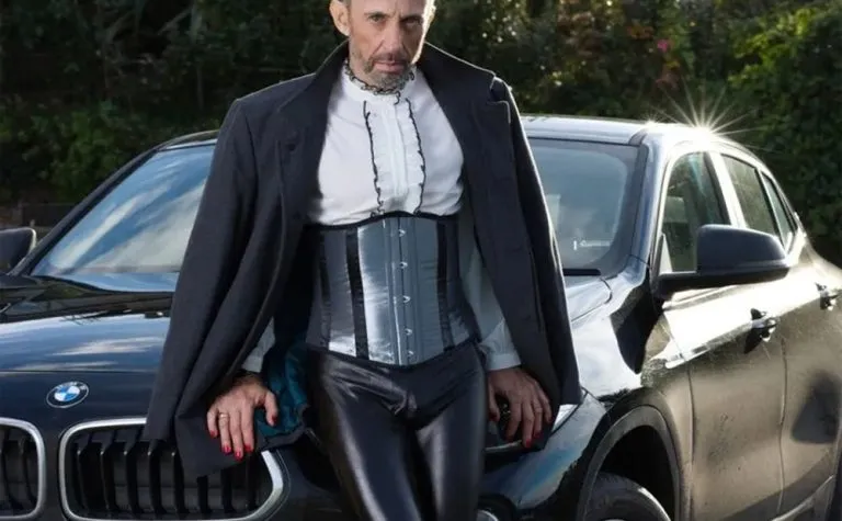 homme élégant en serre taille qui pose sur une voiture