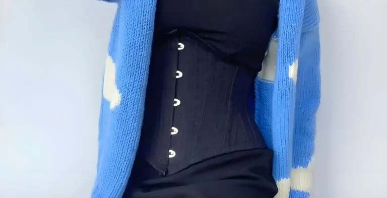 Serre-taille denim bleu foncé porté sur robe longue et gilet pastel